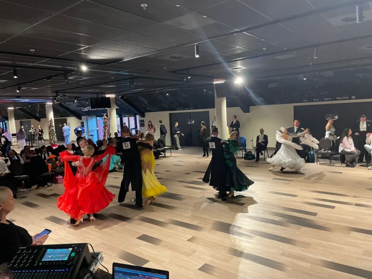 Meerdere dansparen in ballroomjurken op de wedstrijdvloer