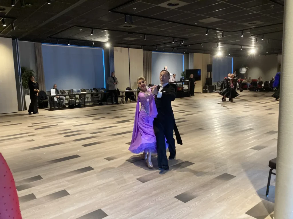 Danspaar in paarse ballroomjurk danst op het parket